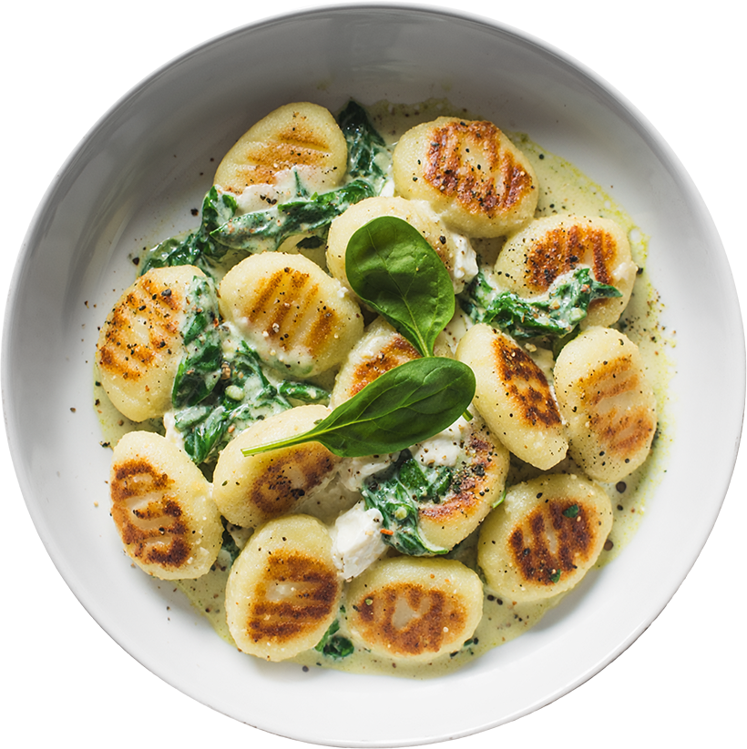 Goldbraun gebratene Gnocchi mit frischem Spinat und cremiger Frischkäse-Alternative in einer Pfanne angerichtet.