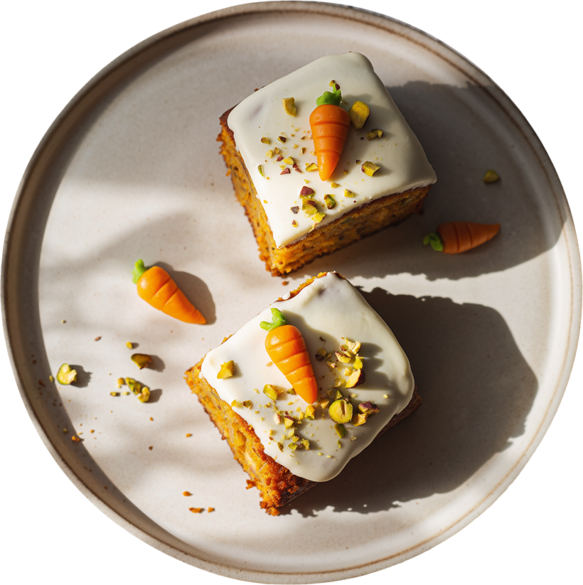 Veganer Karottenkuchen mit Frischkäse-Frosting und kleinen Marzipan-Karotten auf einem Teller