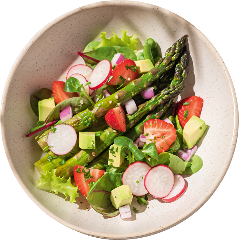 Frischer Frühlingssalat mit grünem Spargel, Erdbeeren, Radieschen, Blattsalat und Avocado in einer hellen Schüssel.