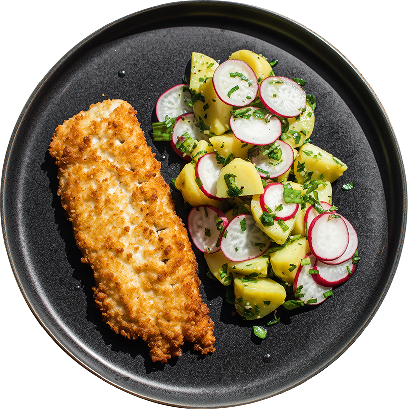 Knusprig panierter Fisch mit Kartoffel-Radieschen-Salat auf schwarzem Teller – FoodKalender KW22 vom 25.05. bis 31.05.