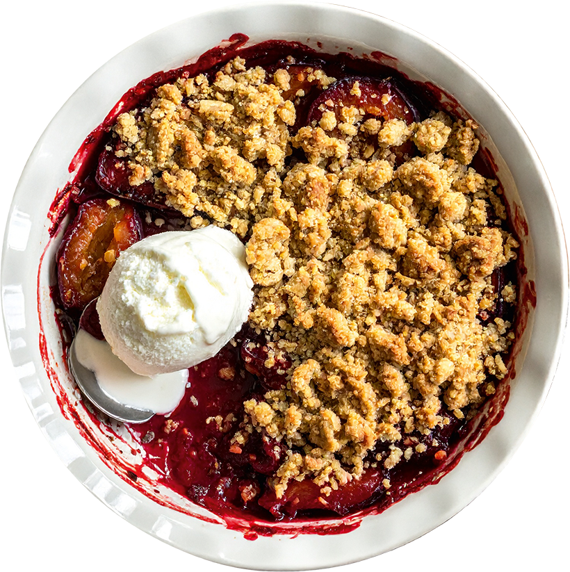 Pflaumen-Crumble mit knusprigen Haferstreuseln und einer Kugel Vanilleeis in einer Auflaufform serviert.