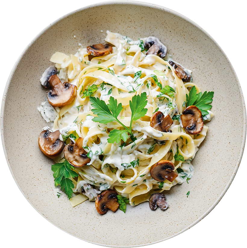 Cremige Pilz-Tagliatelle mit Champignons, Frischkäse, frischen Kräutern und Petersilie auf einem Teller angerichtet.